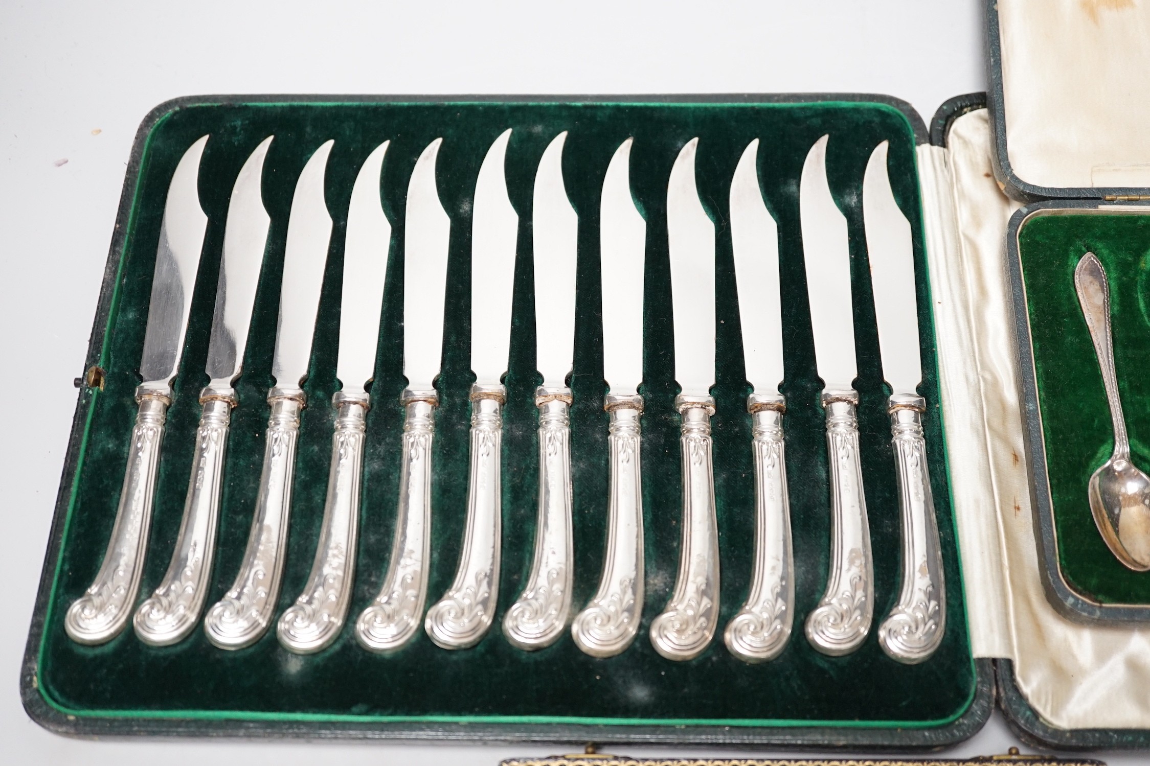 A cased set of twelve silver handled dessert knives, six seal-top teaspoons, five (ex 6) teaspoons and tongs.